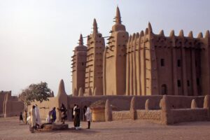 Bamako, Segou and Djenne Hiking, Culture and Arts 8-Day Tour A group of people gather near the Great Mosque of Djenné, a large mud-brick building with towers and wooden scaffolding, in Djenné, Mali.