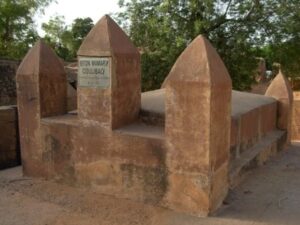 Bamako, Sikasso, and Segou 5-Day Arts and Culture Tour This is a tomb structure with a plaque identifying it as Biton Mamary Coulibaly's. It is built of a reddish-brown material with a flat top and pointed towers at each corner.